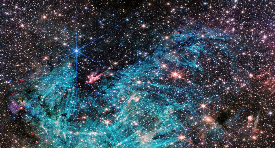 Many stars clustered together, with a cyan-colored wispy cloud structure across the center