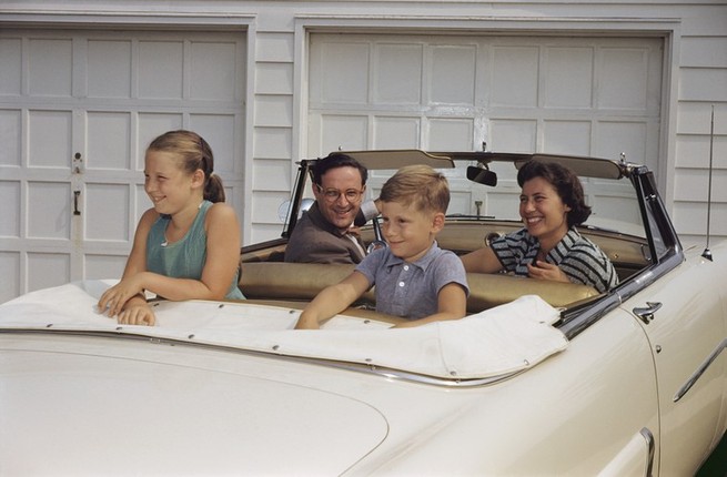 A family sits in a white convertible