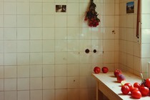 A brightly lit room with tiled walls and a table with tomatoes and peaches on them