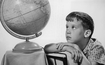 A young man stares at an old-fashioned globe