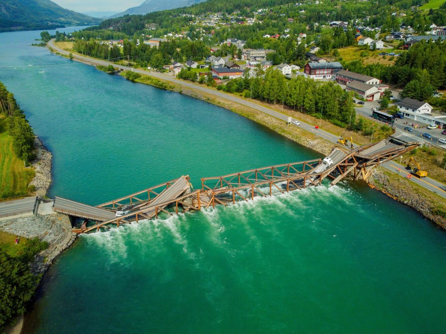 An aerial view of a river with a collapsed road bridge lying across it.