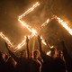 Supporters of the National Socialist Movement give Nazi salutes while taking part in a swastika burning.