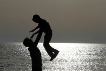 The silhouettes of a father and son playing on the beach