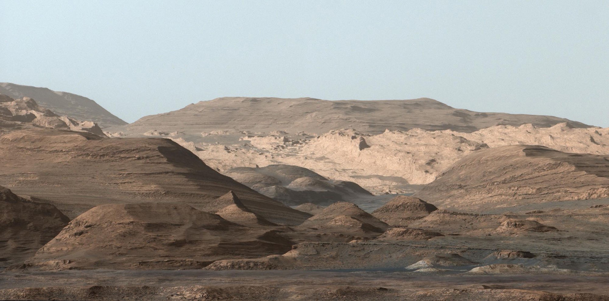 A view of rounded and rocky buttes and valleys on Mars