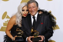 Lady Gaga and Tony Bennett pose while holding Grammy awards.