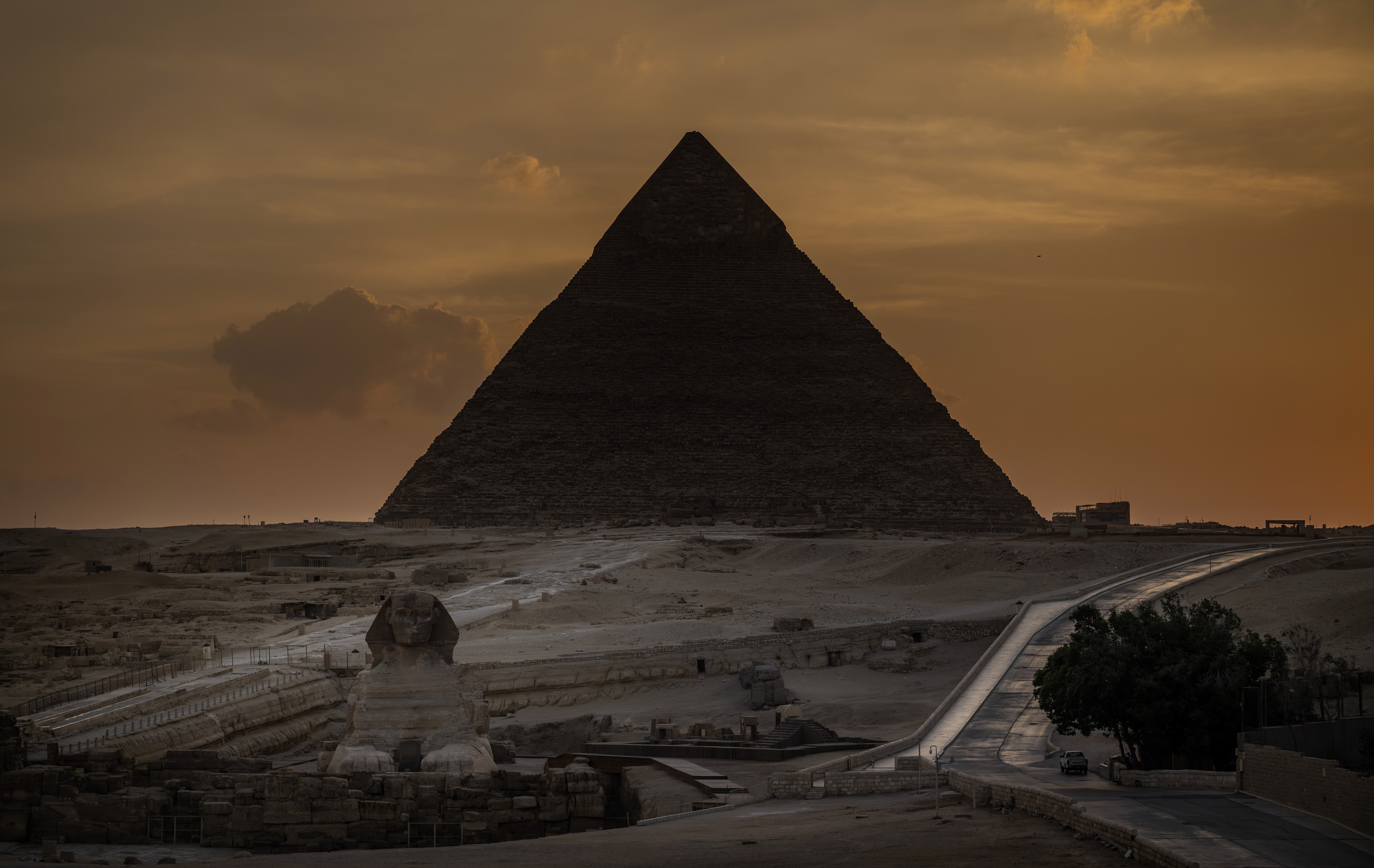 A sunset view of a tall pyramid and the Great Sphinx of Giza in Egypt