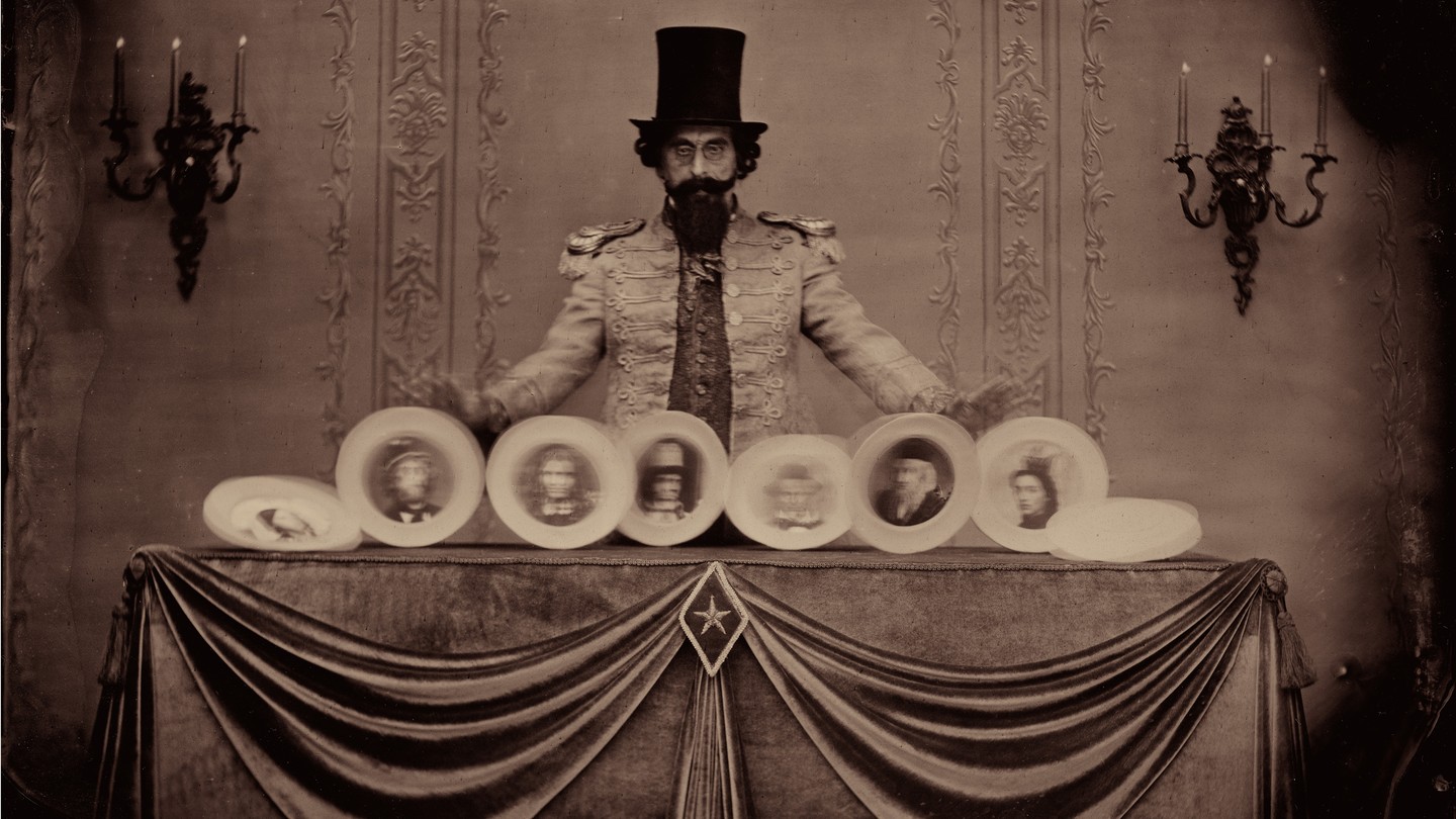 A man wearing a top hat is spinning plates