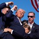 A bloodied Donald Trump fist-pumps as Secret Service rush him offstage.