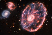 Three large spiral galaxies float in space, surrounded by hundreds of other, more distant galaxies.