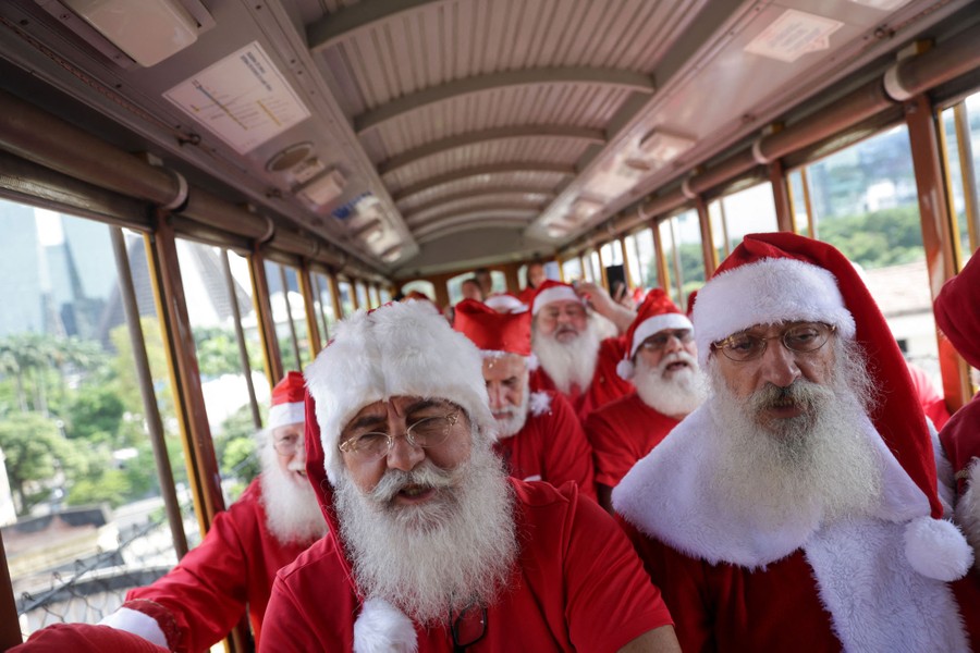 People dressed as Santa ride in a tram.
