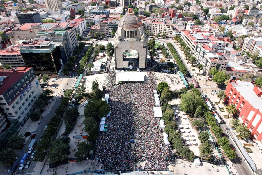 An elevated view of a large crowd gathered in a city plaza.