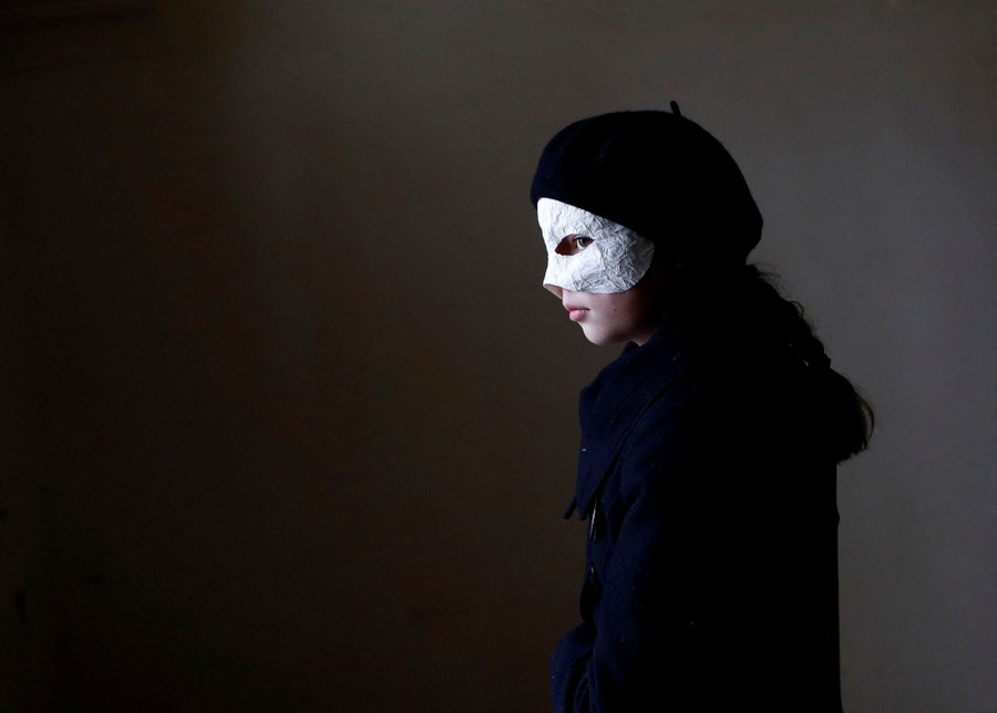 A child stands, wearing a mask.