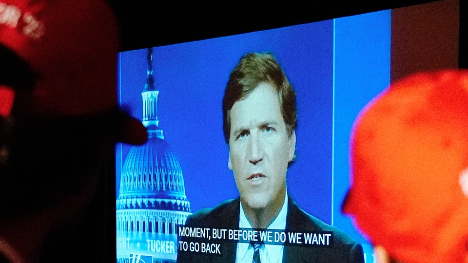 Two people in red caps watching Tucker Carlson's show