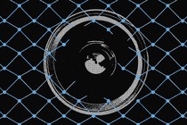 A surveillance camera partially obscured behind some fence-like wiring