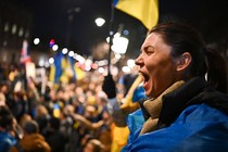 A person shouts among a crowd of protesters waving Ukrainian flags.