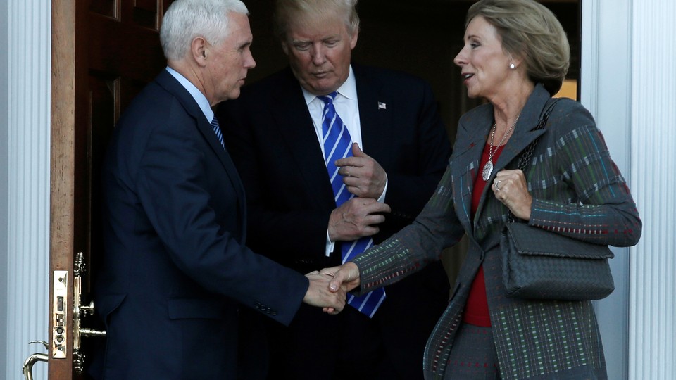 Vice President-elect Mike Pence shakes Education Secretary Appointee Betsy DeVos's hand. President-elect Donald Trump stand between them.