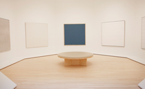 a white room with Agnes Martin's paintings on the wall and a round seat in the center