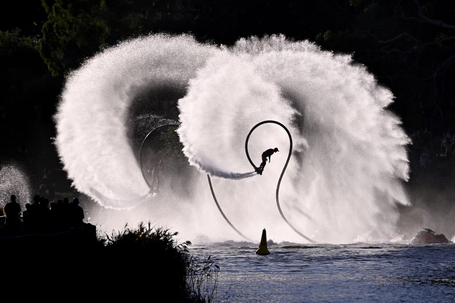 Two people flying water-jet boards splash water in huge spirals.