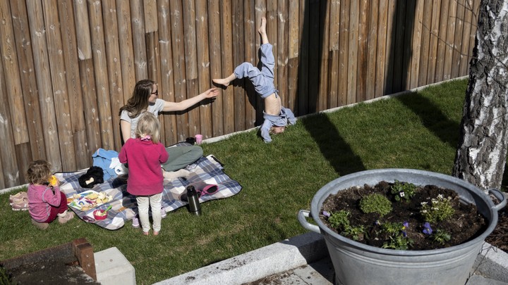 A woman tries to help one child while another stands on his head.