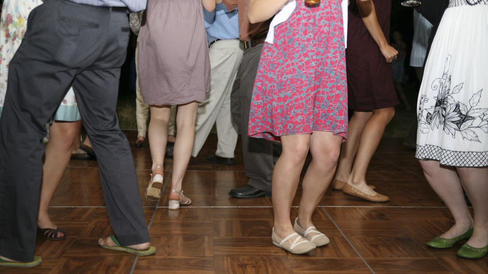 A group of people wearing dresses and slacks dance