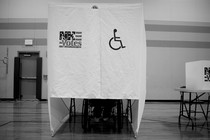 A person using a wheelchair votes at a wheelchair-accessible voting booth.