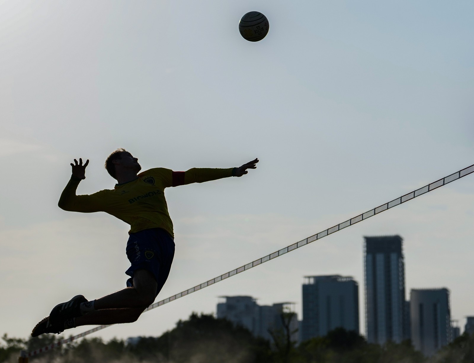 An athlete jumps to hit a ball over a net during a game.