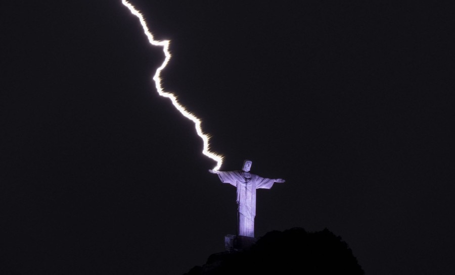 A bolt of lightning strikes the hand of the Christ the Redeemer statue.
