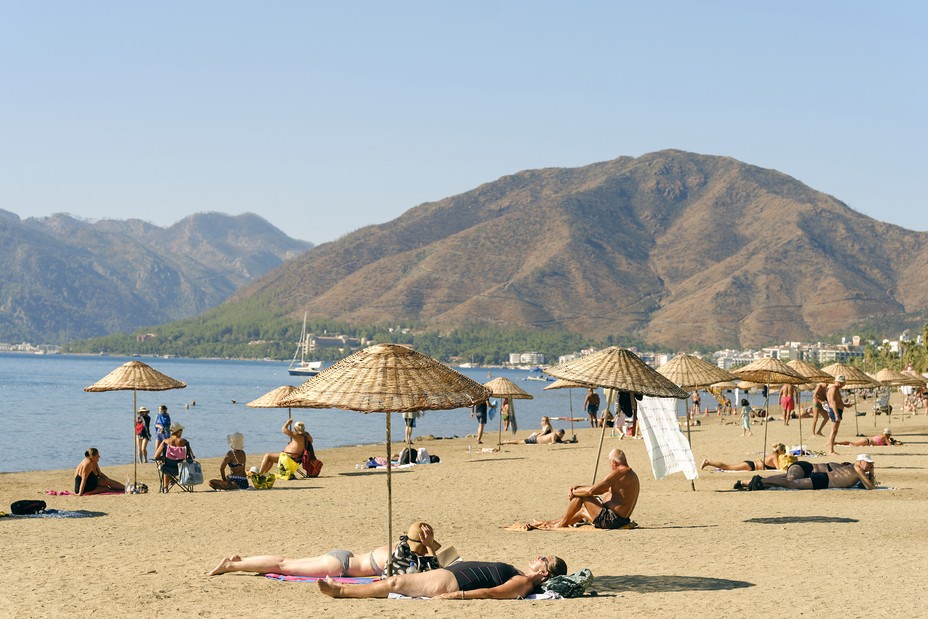 sunbathers on a beach surrounded by burnt hills