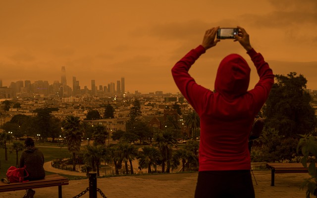 A woman taking a photo of an orange sky