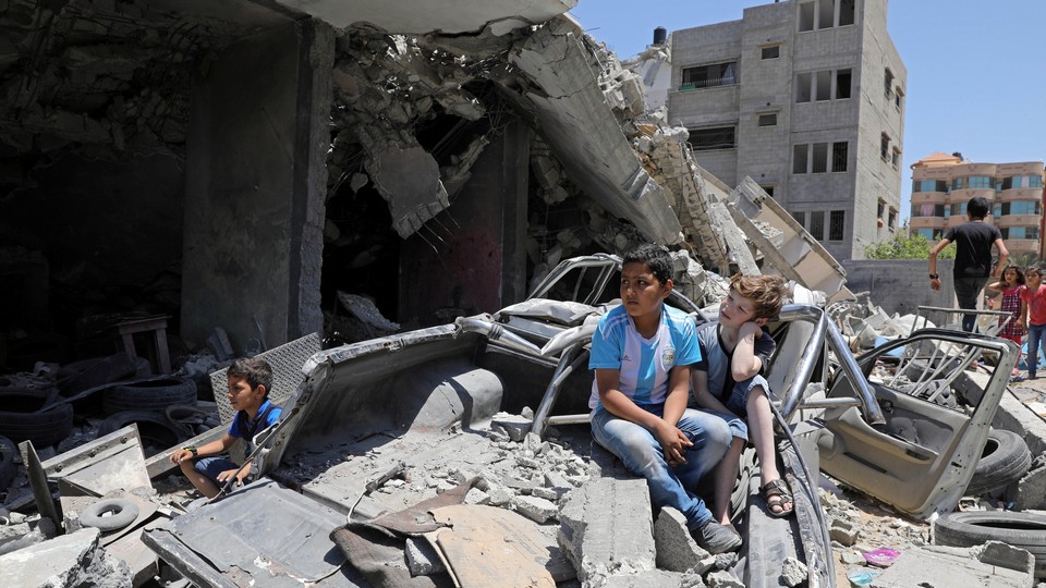 Palestinian children watch a band perform from the rubble of a building destroyed by Israeli air strikes.