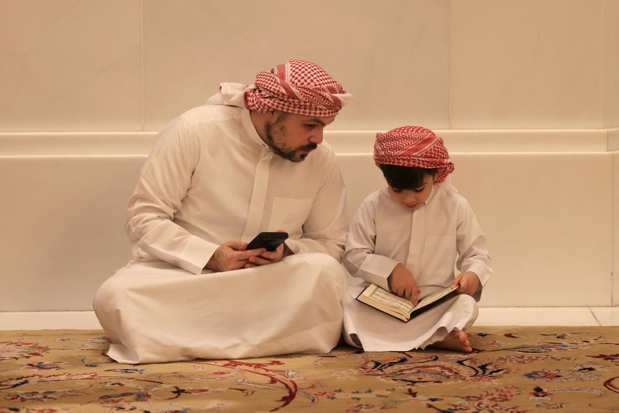 Ένας άντρας και ένα παιδί κάθονται μαζί στο πάτωμα, μελετώντας το Κοράνι.