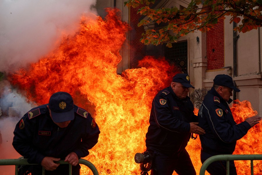 Several police officers duck and run from a rising fire from a Molotov cocktail thrown behind them.