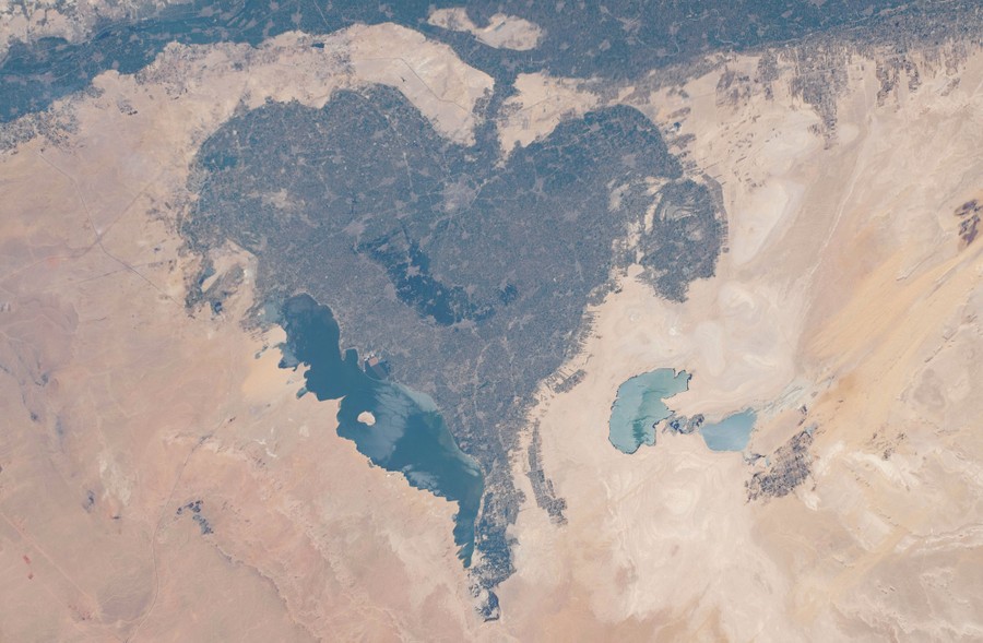 A heart-shaped land formation is seen in a surrounding desert.