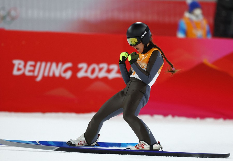 A ski jumper celebrates after landing a jump.