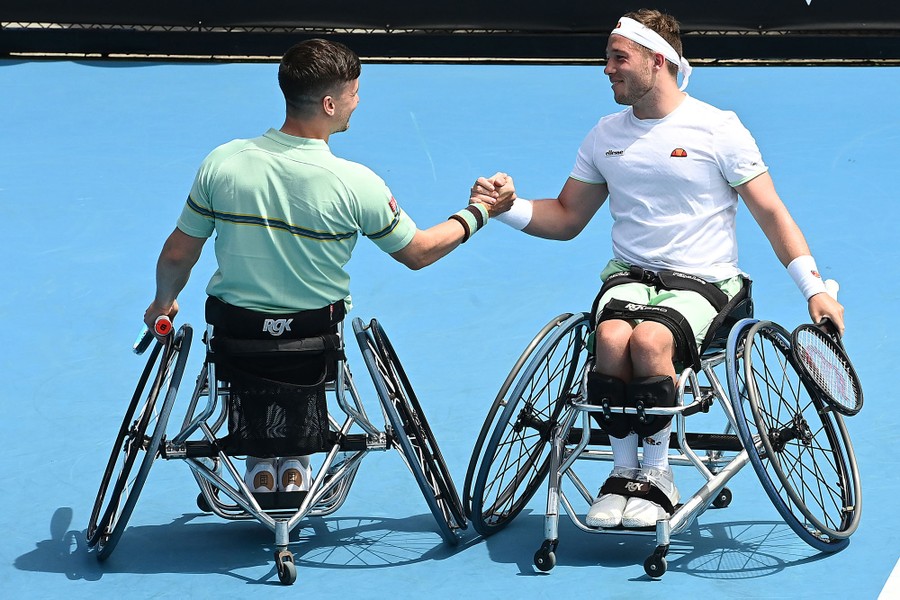 Two players in wheelchairs grasp hands on the court.