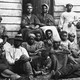 A black-and-white image of Black Americans in front of a cabin
