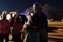 Two people embrace at a nighttime vigil.