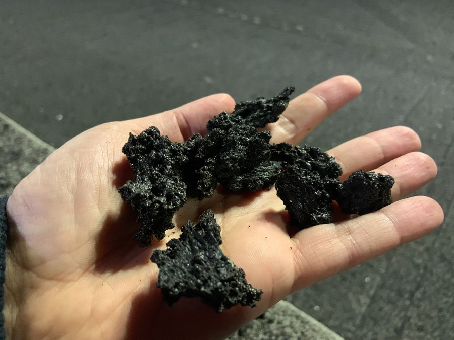A person holds small chunks volcanic material.