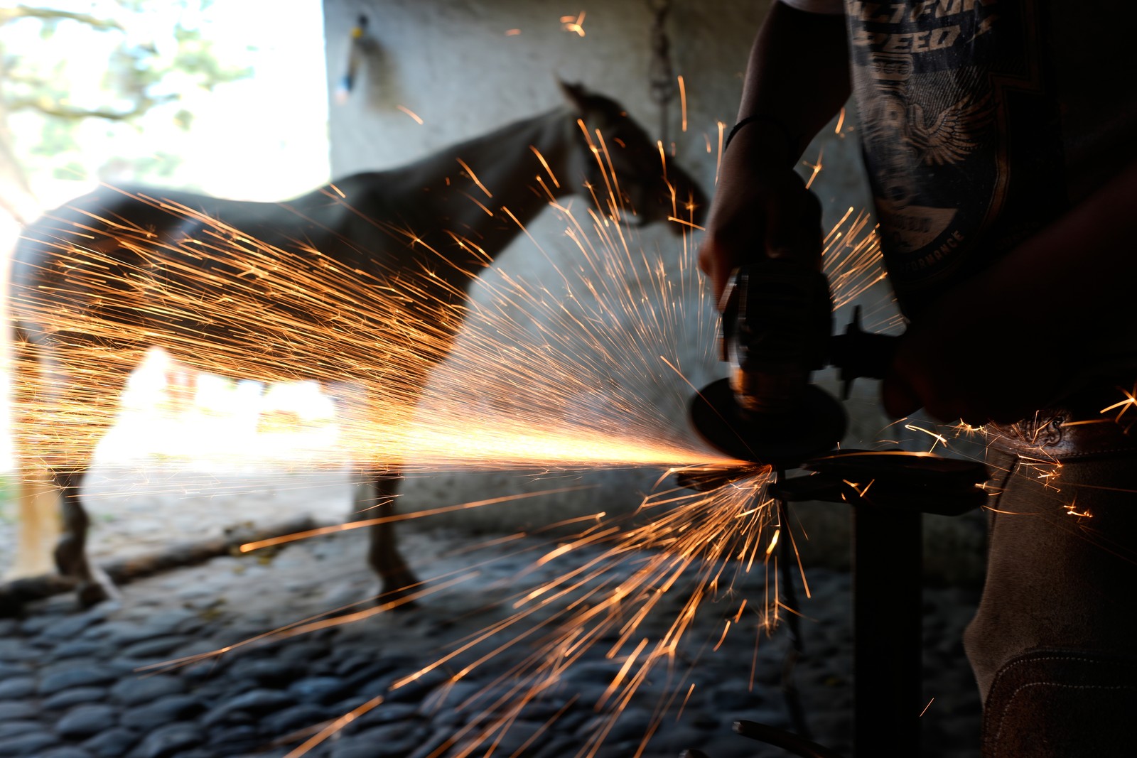 Sparks fly as a blacksmith prepares horseshoes.
