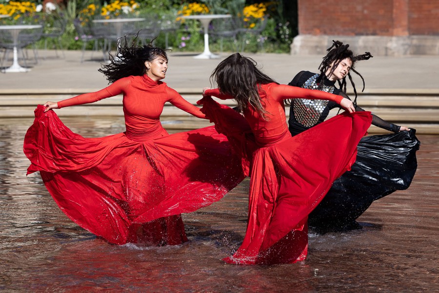Three dancers perform in a shallow fountain.