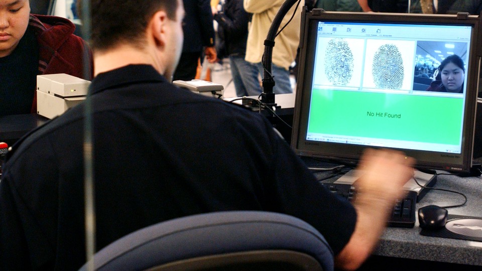 A U.S. Customs and Border Protection agent checks an overseas visitor's fingerprints and image in a database.