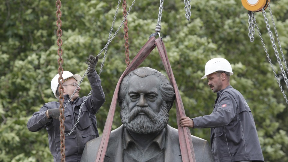 Workers in Berlin attach chains to lift a statue of Karl Marx.