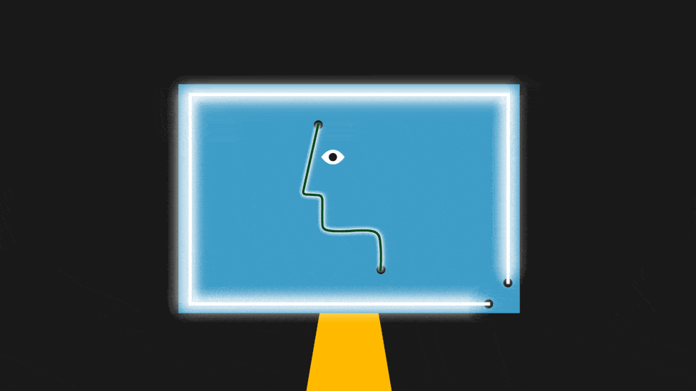 A computer monitor has a glowing light on its edges and a blinking face in its middle.
