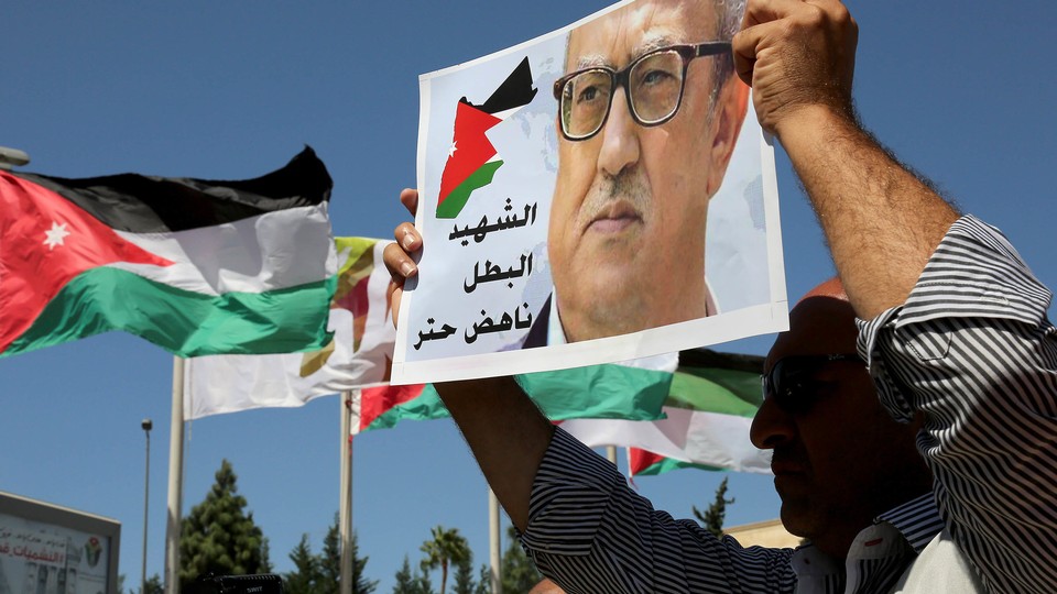 Protesters hold up photos of Jordanian writer Nahed Hattar outside the Jordanian Prime Ministry in Amman, Jordan. 