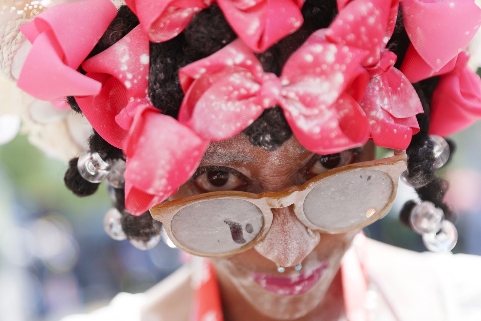 A person with many bows in their hair poses before a parade.