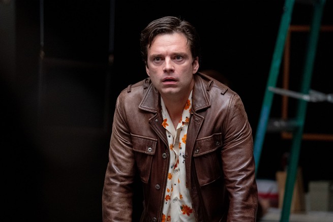 A man in a brown leather jacket looking concerned and scared