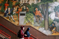 Two students walk down steps past a historical mural at George Washington High School in San Francisco.