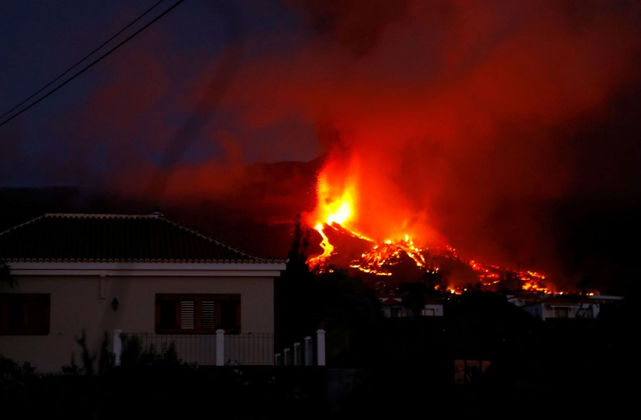 Lava flows near houses, seen at night.