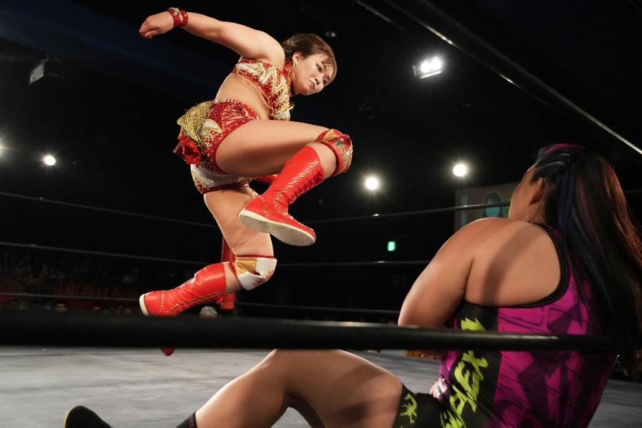 A pro wrestler jumps toward another inside a ring.