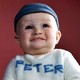 A photograph of a baby wearing a sweater that says "Peter" on it